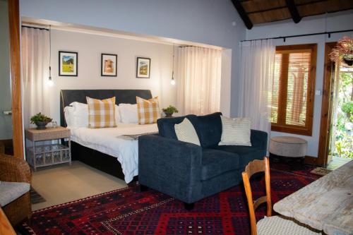 比勒陀利亚舍伍德小屋酒店的一间卧室，里面有一张床、一张沙发和一把椅子