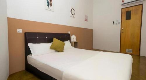 1 dormitorio con 1 cama blanca grande con almohada amarilla en OYO Home 90554 Norfa Camp House, en Kampong Tanah Baharu