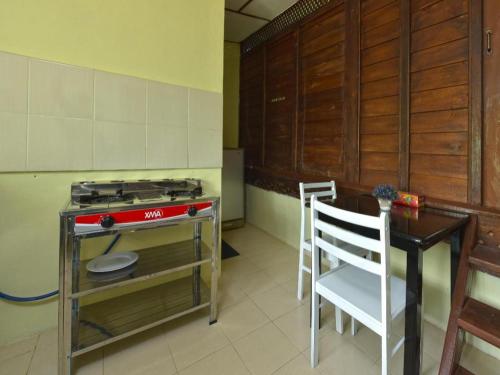 a kitchen with a stove and a table and a chair at Collection O 90622 Sehijau @ Cenang in Pantai Cenang