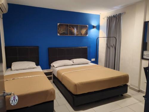 two beds in a room with a blue wall at Vitro Hotel in Johor Bahru