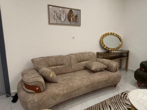 un divano marrone in un soggiorno con specchio di Le Prestige Appartement à Oloumi a Libreville
