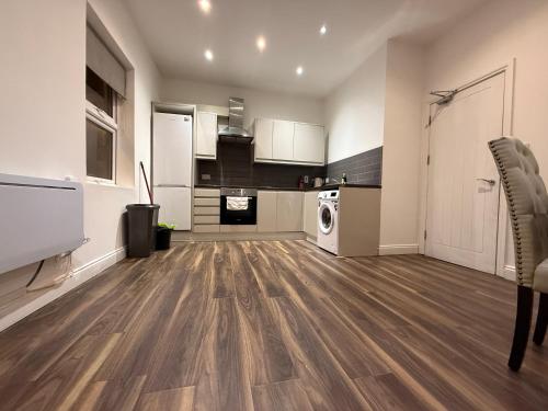 a large kitchen with white cabinets and wooden floors at Belin Stay in Hackbridge