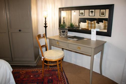 比勒陀利亚舍伍德小屋酒店的酒店房间里的一张桌子、一把椅子和一面镜子