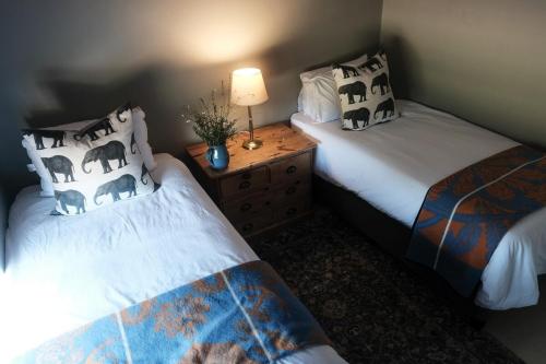 霍维克The Scottage的一间卧室，有两张床和一张带灯的桌子