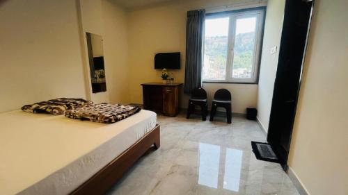 a bedroom with a bed and a desk and a window at legacy of chittorgarh in Chittaurgarh