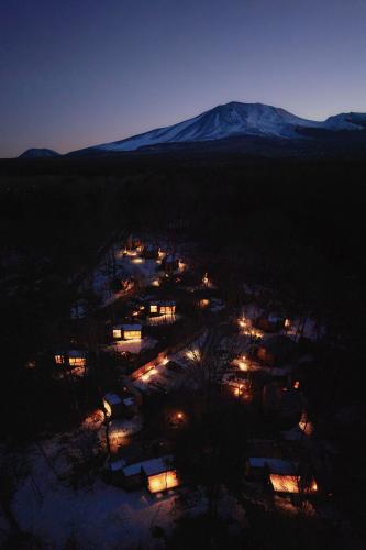 an aerial view of a village at night with a snow covered mountain at SANU 2nd Home 北軽井沢 1st in Naganohara