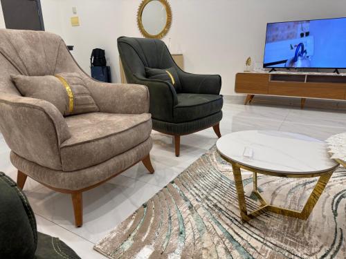 a living room with two chairs and a tv at Le Prestige Appartement à Oloumi in Libreville