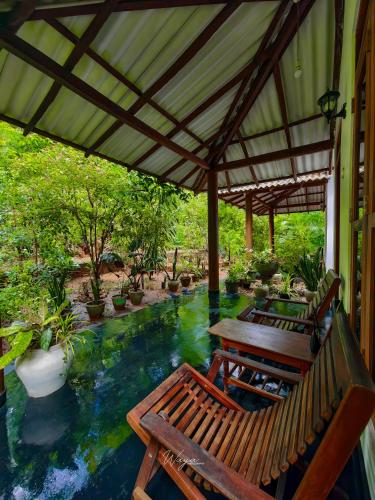 a patio with two benches and a table and a pool at Bright Sun Safari in Udawalawe