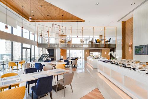 a restaurant with white tables and chairs and windows at The Quarter Ari by UHG in Bangkok