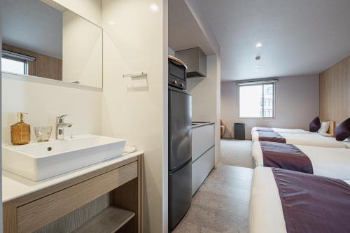 a bathroom with a sink and two beds in a room at グランドベースMirai 長崎駅徒歩8分 in Nagasaki