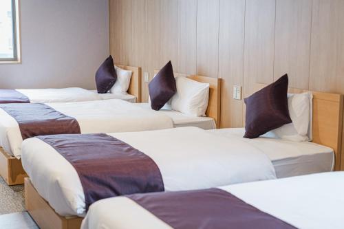 a room with four beds with pillows on them at グランドベースMirai 長崎駅徒歩8分 in Nagasaki