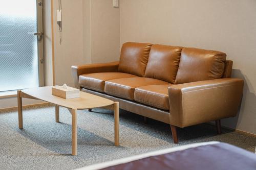 un sofá de cuero marrón en una sala de estar con mesa de centro en グランドベースMirai, en Nagasaki