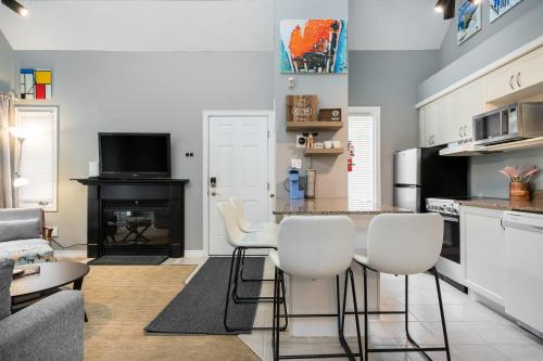 un salon avec une cuisine équipée d'un bar et de chaises blanches dans l'établissement Blue Haven Ski-In-Out Pool Hot Tub Shuttle, à Blue Mountains