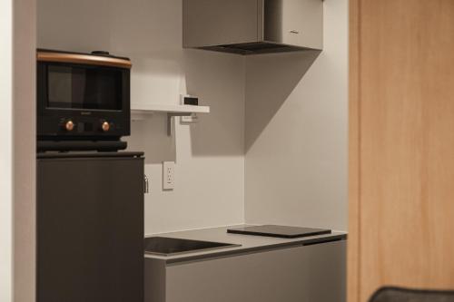 a small kitchen with a microwave and a refrigerator at グランドベースMirai 長崎駅徒歩8分 in Nagasaki
