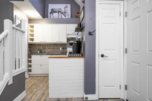 een keuken met witte kasten en een schilderij van een paard op de muur bij Fox Ridge - Ski-In-Out Pool Hot Tub Shuttle in Blue Mountains