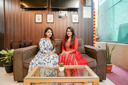 two women sitting on a couch in a room at FabHotel Komfort Inn - Nr Twin Tower in Yeraoda