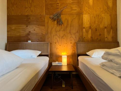 two beds in a room with a lamp on a table at Hostel Fuji Matsuyama Base in Fujiyoshida