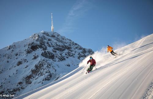 Due persone che sciano giù da una montagna innevata di Gartenhotel Rosenhof bei Kitzbühel a Oberndorf in Tirol