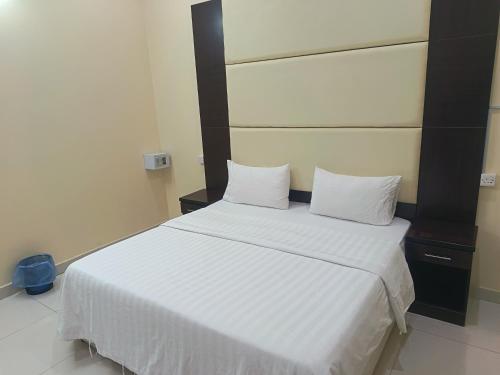 ハーイルにあるروعة أجا للشقق المخدومة غرفة وصالةの白いベッドと枕が2つある寝室