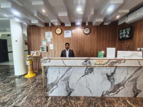 ハーイルにあるروعة أجا للشقق المخدومة غرفة وصالةのロビーの窓口の後ろに立つ男