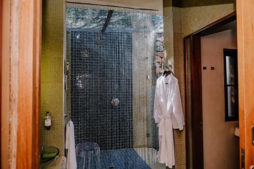 a shower stall in a bathroom with a robe on it at Forum Homini Boutique Hotel in Krugersdorp