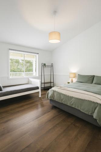 a white bedroom with a bed and a window at Cocora Beach Cottage - pet friendly in Eden