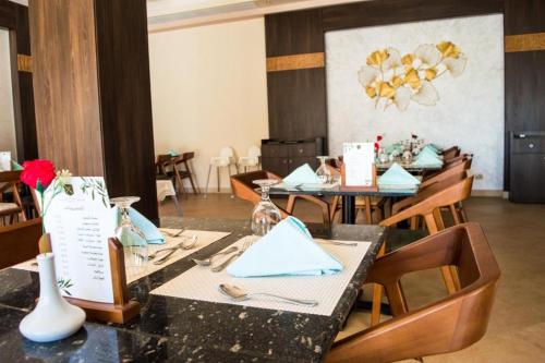 a dining room with tables and chairs with blue napkins at Oyster Bay Beach Suites in Marsa Alam