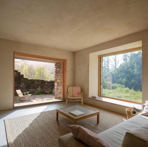 a living room with a couch and a large window at Casa Mínima retiro Passivhaus in Selaya