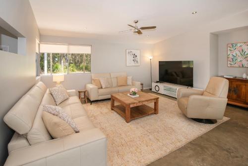 a living room with a white couch and a tv at Sequoia Sanctuary - Margaret River in Margaret River Town