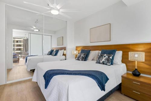 una camera da letto con due letti e uno specchio di Marina Vista - Waterfront Stay near Dining and Markets a Cairns