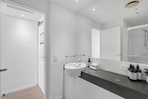 un bagno bianco con lavandino e doccia di Marina Vista - Waterfront Stay near Dining and Markets a Cairns