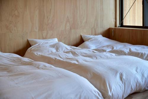 two white beds sitting next to a window at SANU 2nd Home Ichinomiya 2nd in Ichinomiya
