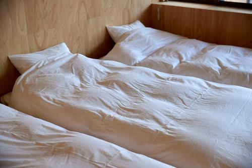 an unmade bed with white sheets and pillows at SANU 2nd Home Ichinomiya 2nd in Ichinomiya