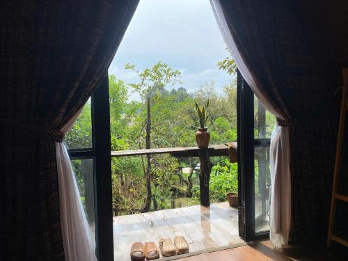 ein Fenster mit Blick auf ein Zimmer, in dem Sandalen auf dem Boden stehen. in der Unterkunft Buôn Gơ Rin in Láng Lớn