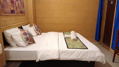 Hotel Al-raya Jaisalmer في جيلسامر: سرير في غرفة بشرشف ووسائد بيضاء
