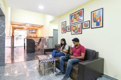two people sitting on a couch in a room at FabHotel Olive Inn I - 260m from Saltlake Sector V Metro Station in Kolkata