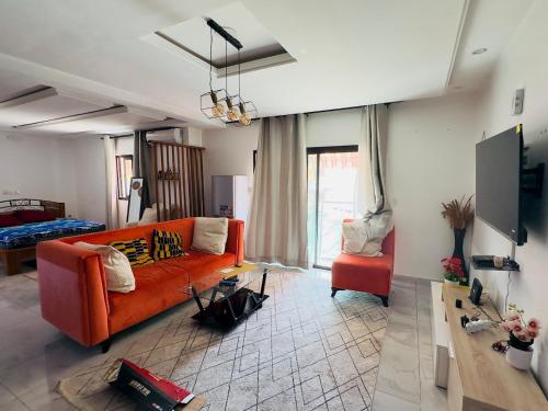 sala de estar con sofá naranja y silla roja en Résidence Karima, en Abiyán