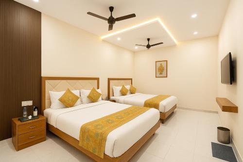 una camera d'albergo con due letti e un ventilatore a soffitto di HOTEL BNK GRAND Near Goḏawalia Chauraha - 100 Meter From Baba Vishwanath Temple & Ganga Arti Ghat ! Wi-Fi #Lift #Hygiene & Spacious Room - BEST HOTEL IN VARANASI a Varanasi