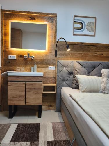 a bathroom with a sink and a bed and a mirror at Appartement Rehlein in Mauterndorf