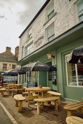 a group of picnic tables and umbrellas outside of a building at The Pennine Inn in Kirkby Stephen