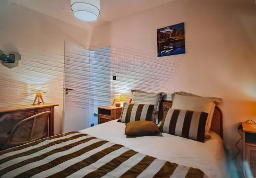a bedroom with a bed with striped pillows at Location Appartement Les Ondes in Albertville