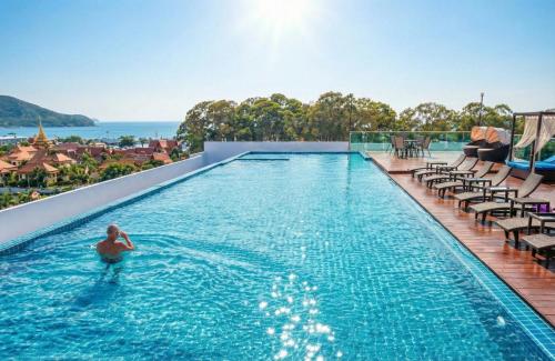 a man in a swimming pool on the roof of a building at Sea saran Condominium - Modern & nature Studio in Bang Sare