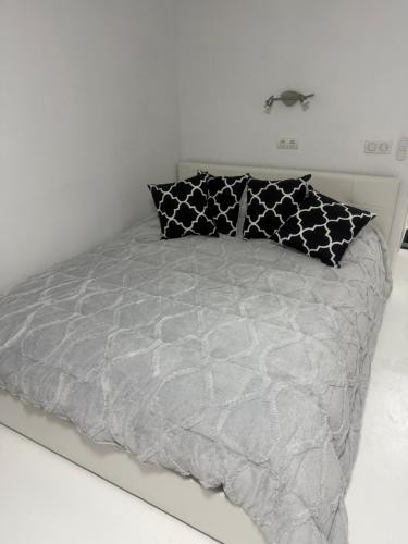 a bed with black and white pillows on it at Studio La Calita in Mijas Costa