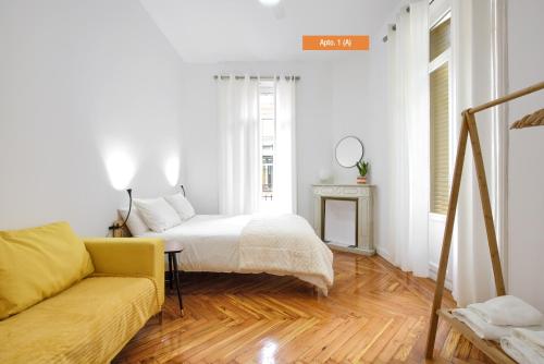 a white room with a bed and a couch at MEZZANINE ORANGE in Madrid