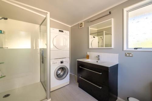 a bathroom with a washing machine and a sink at Onetangi Ocean View - Waiheke Island in Waiheke Island