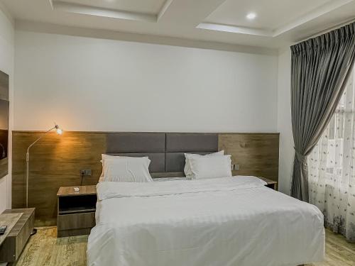 a bedroom with a large white bed with a wooden headboard at Blooms Manor Apartments in Lagos
