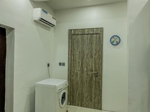 a bathroom with a washer and a wooden door at Blooms Manor Apartments in Lagos