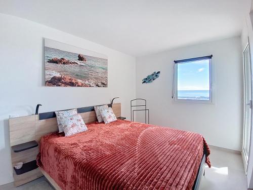 a bedroom with a bed with a red comforter and a window at Appartement lumineux avec vue mer magnifique dans le Domaine du Grand Duc in Mandelieu-la-Napoule