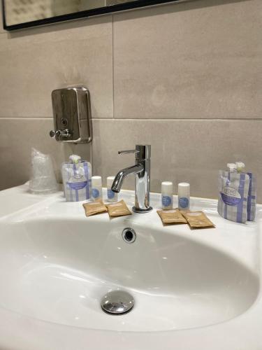 a bathroom sink with a faucet and toiletries on it at Hotel Stradivari in Milan