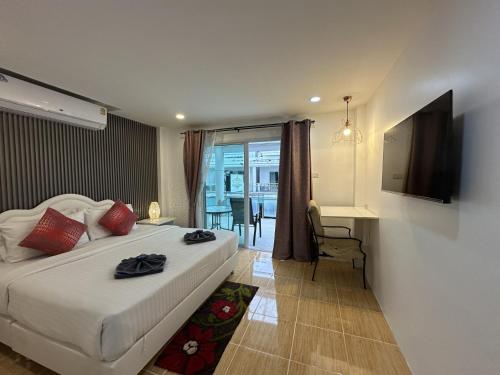 a bedroom with a bed and a desk and a television at Inn Dulgence in Patong Beach